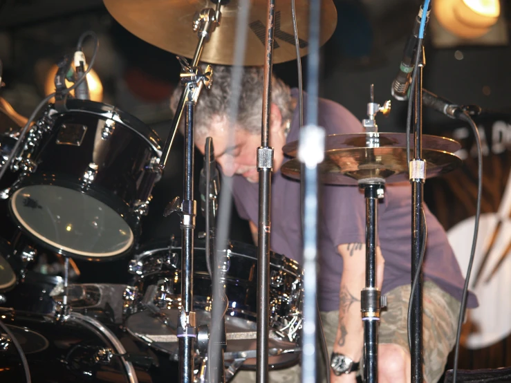 a man is sitting with drums while playing the guitar