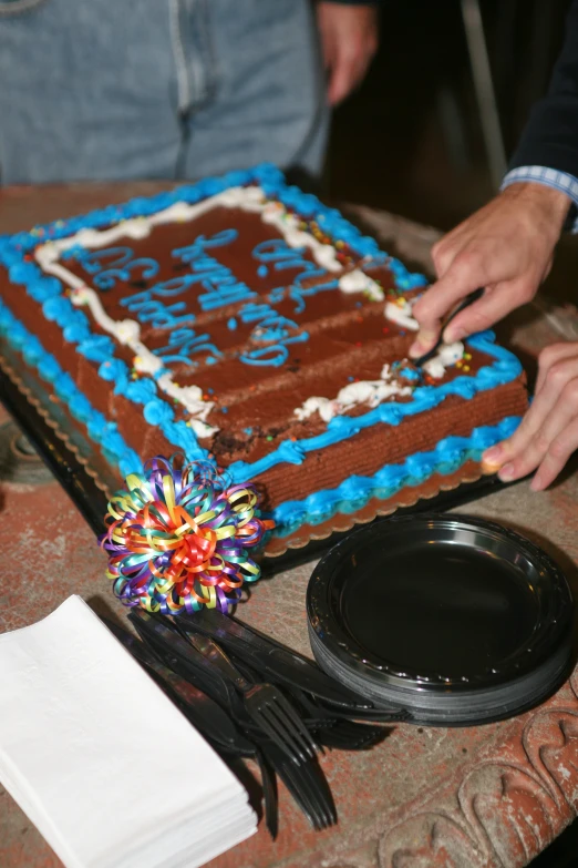 a person cuts into a large brown and blue cake