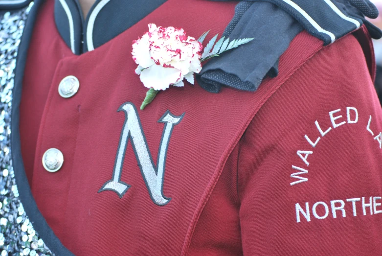 a uniform is adorned with a white carnation and a blue ribbon