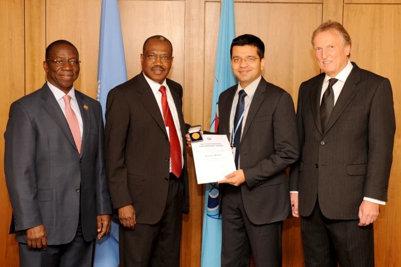 three men are holding an award at a ceremony