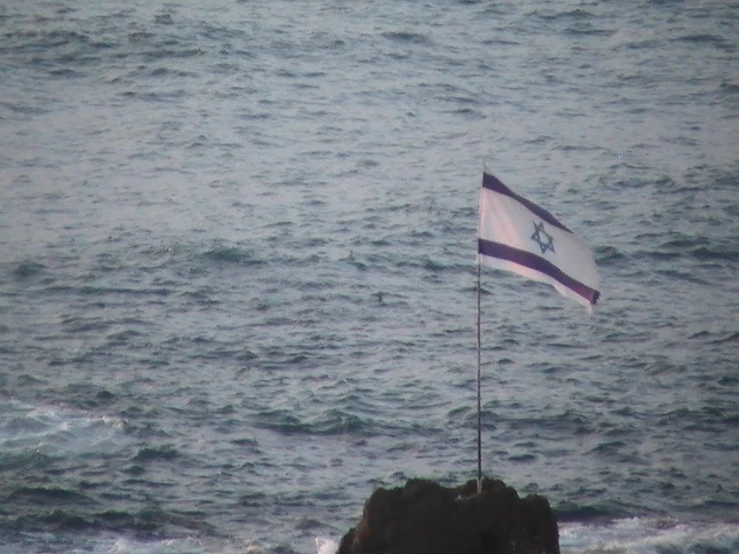 an israeli flag is in the water off the cliff