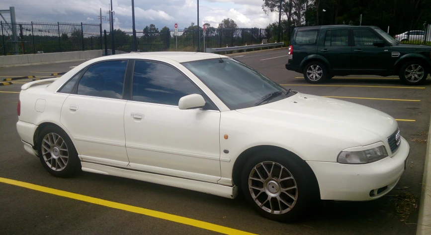 a white car with rims is sitting in the parking lot