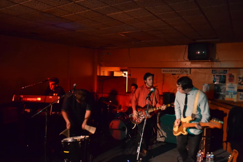 two musicians play in a small bar with red lighting