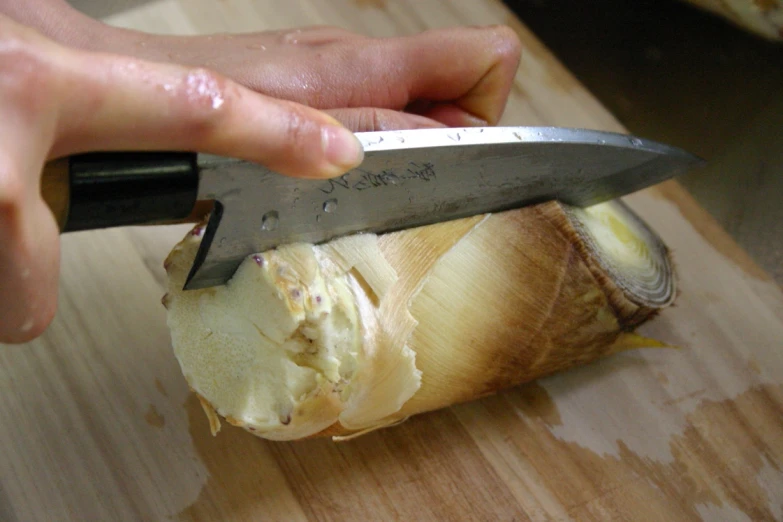 a hand holding a knife  through a piece of food