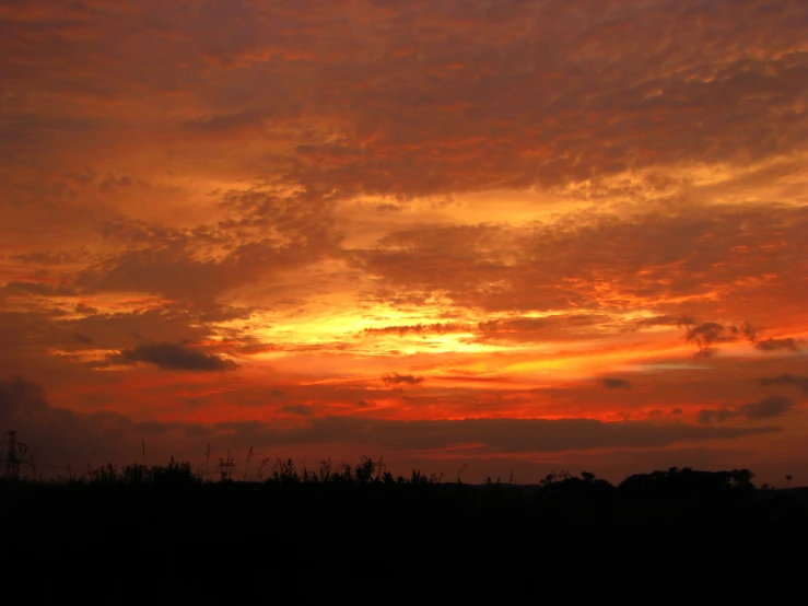 the sun sets with very few clouds above it