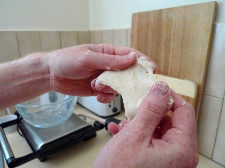 a man hands open a burrito that has been placed in a pan on the stove