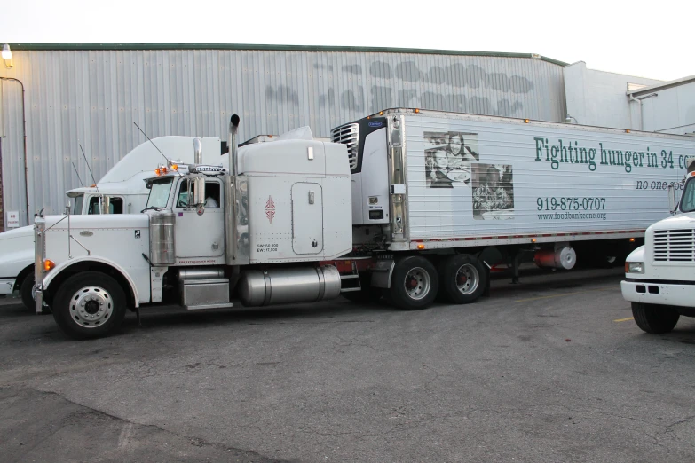 two white semi trucks parked in front of a building