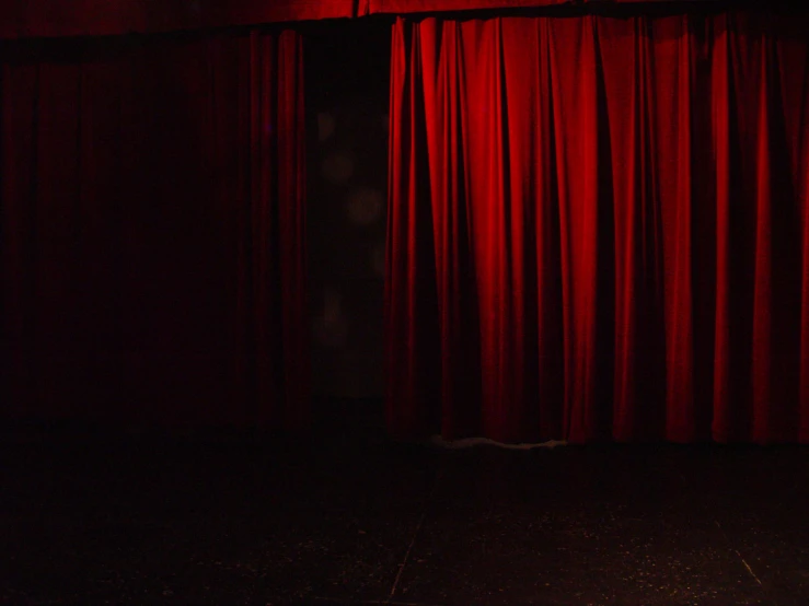 a dark stage with a red curtain at night