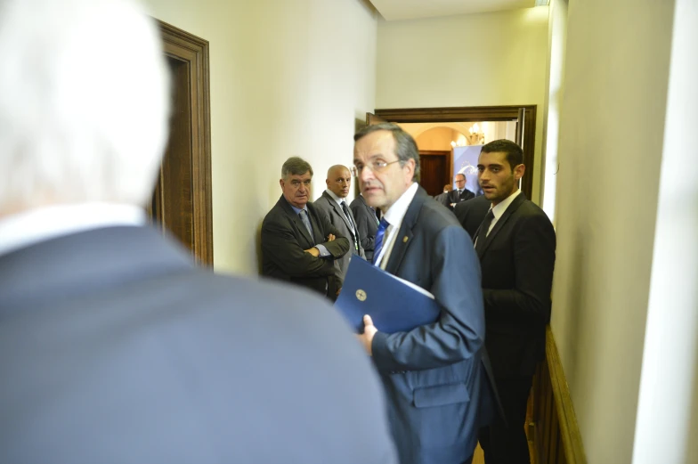 the group of men are standing in a hallway