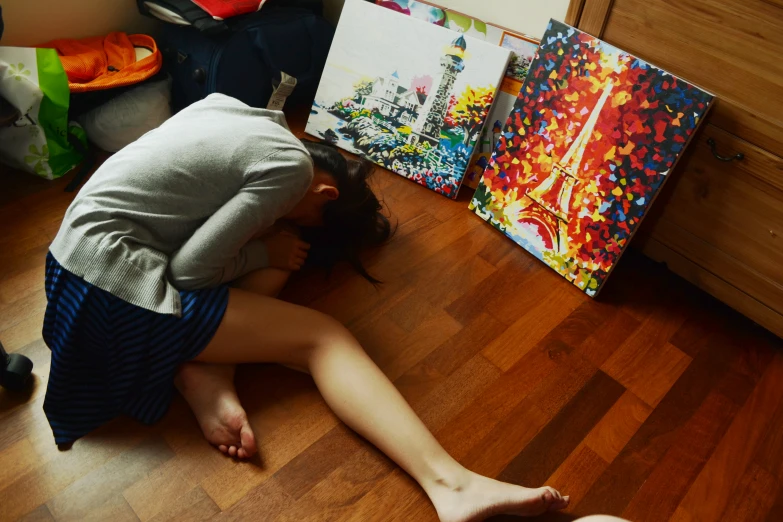 a woman kneeling down in a room near art