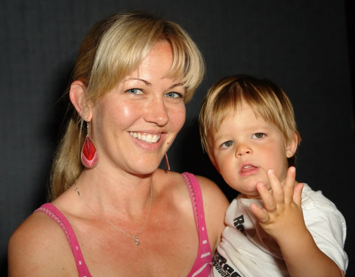 woman with blonde hair and baby in her lap smiling at the camera