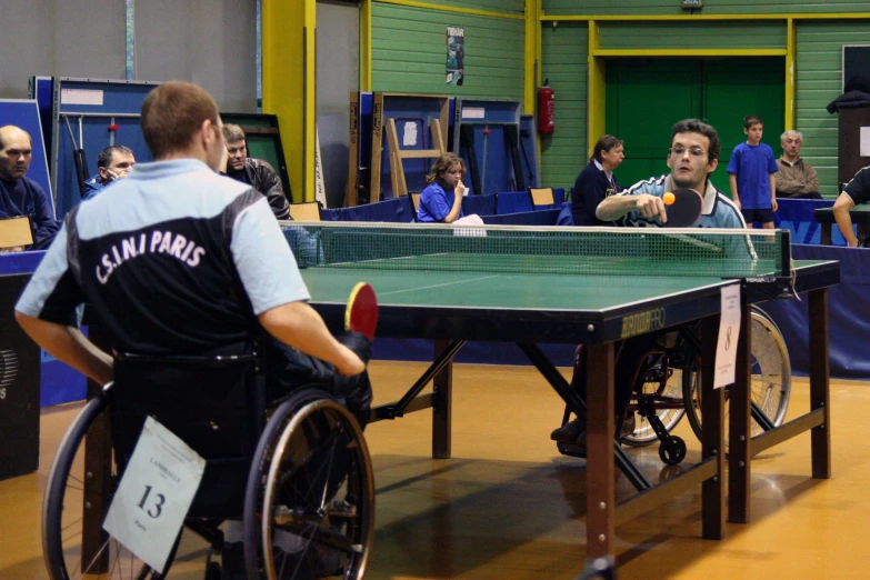 two people in wheelchairs playing ping pong