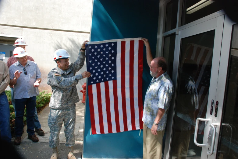 an american flag being displayed with two men