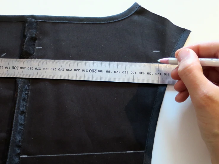 someone measuring out a fabric piece of clothing