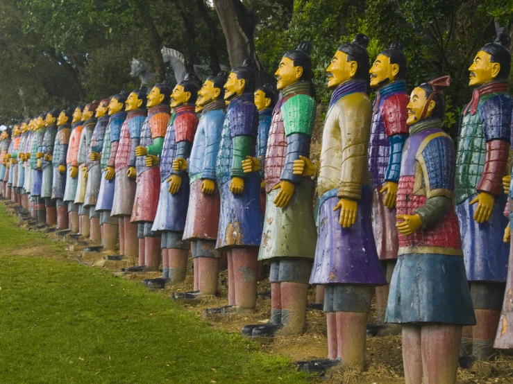 a large number of statues of people lined up on the lawn