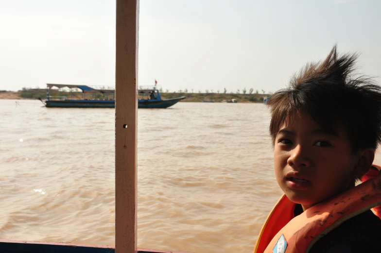 woman in life jacket standing on boat with boats behind her