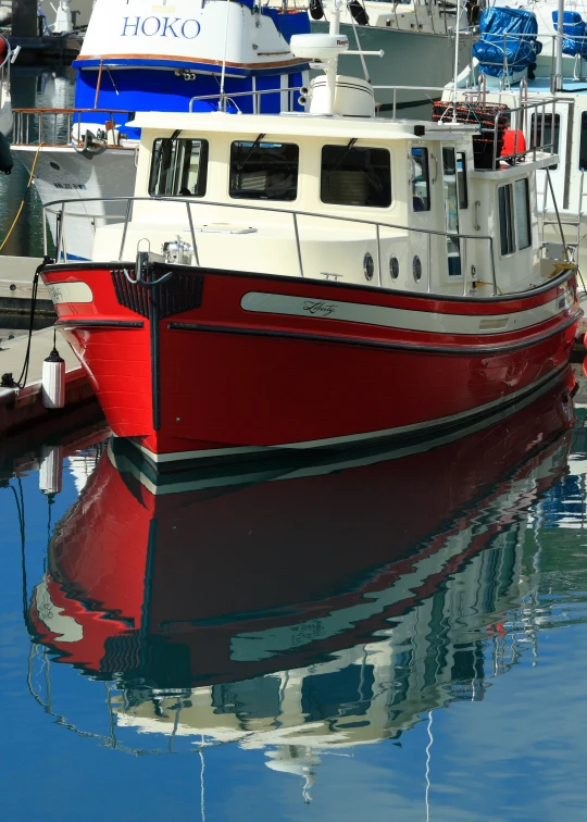 a red and white boat in the harbor with several other boats