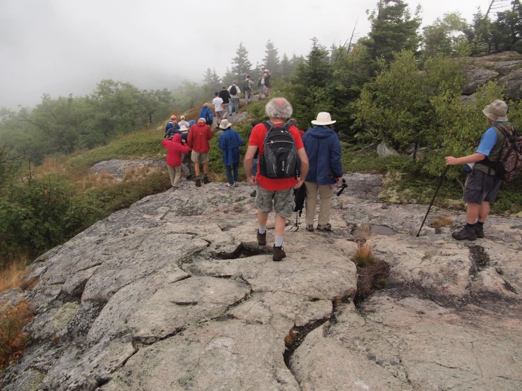 a group of people with backpacks walking up a rocky area