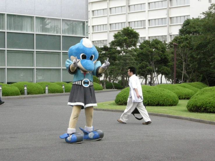 a person walking past a large blue animal mascot
