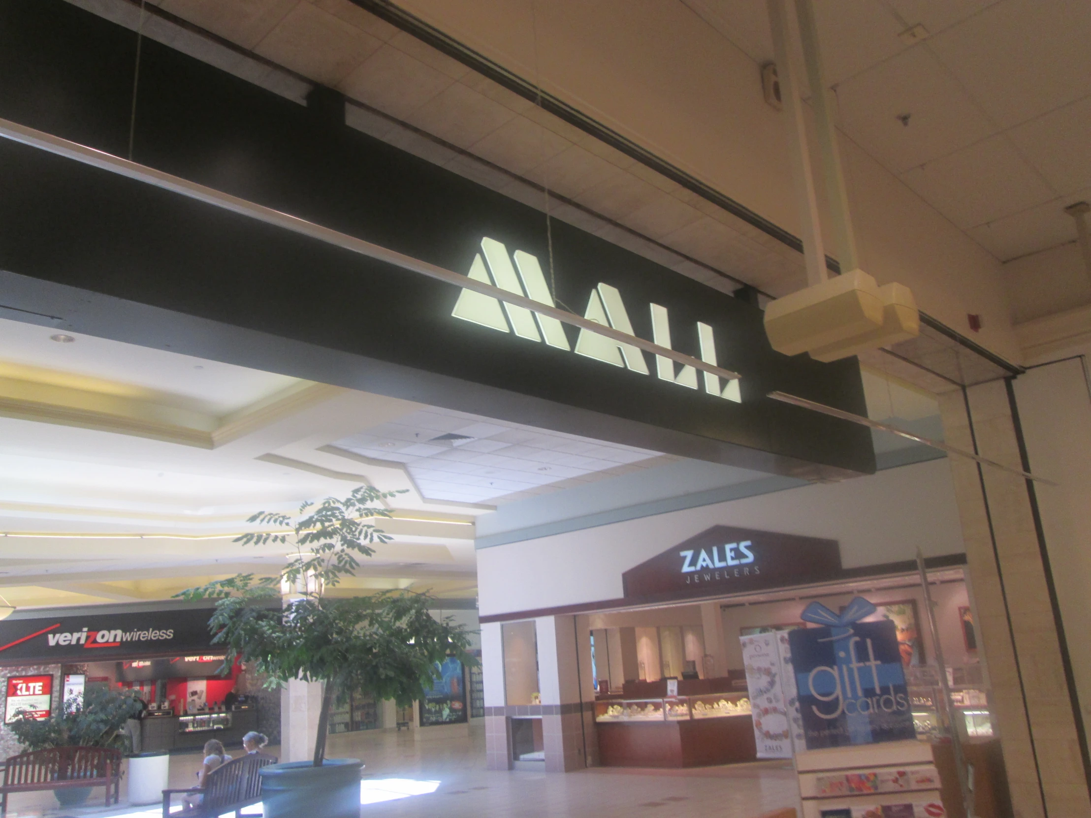 an overhead sign reads mall entrance in an airport