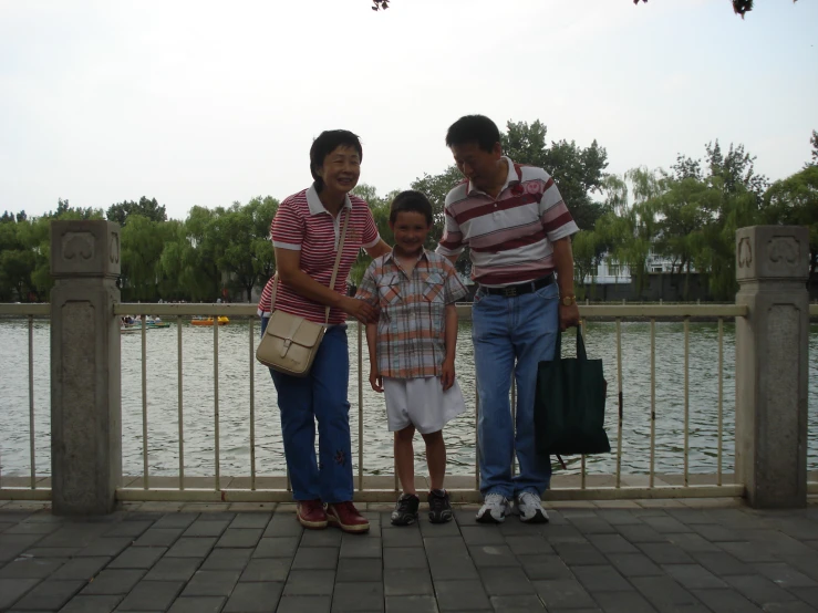 three people standing in front of a lake