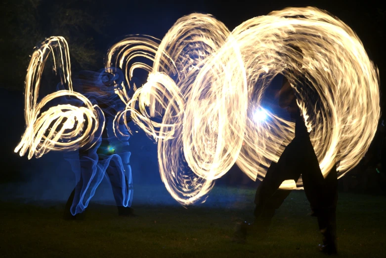 people stand on the grass holding a large circle of fire