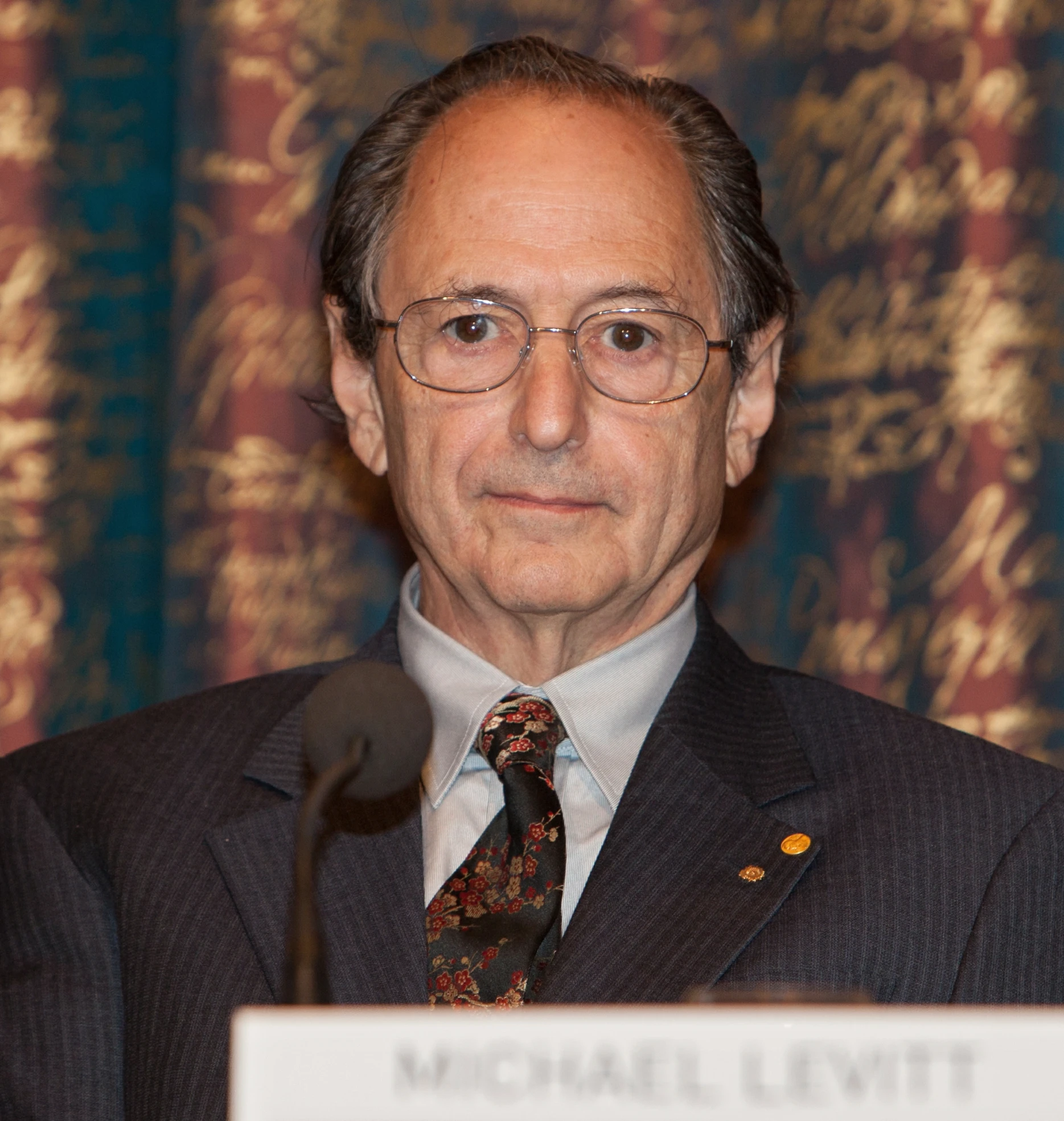 a man speaking at a podium while wearing a suit and tie