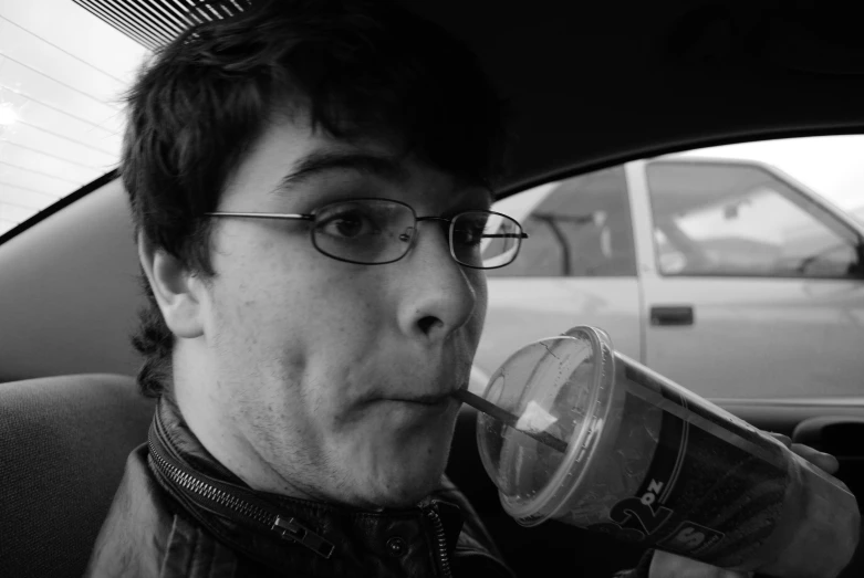 a man in glasses drinking from a plastic cup