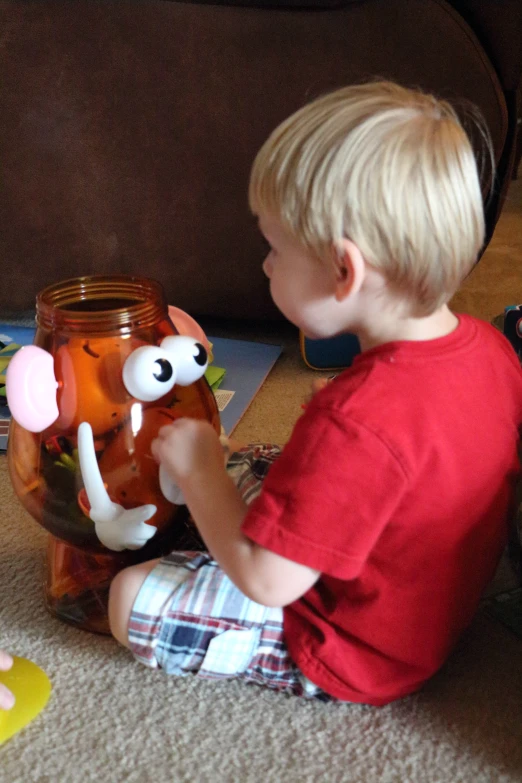 a little boy playing with a toy in front of a vase