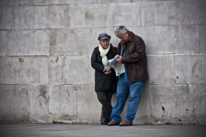 an older couple are reading the newspaper together