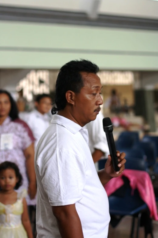 a man in white shirt singing into microphone