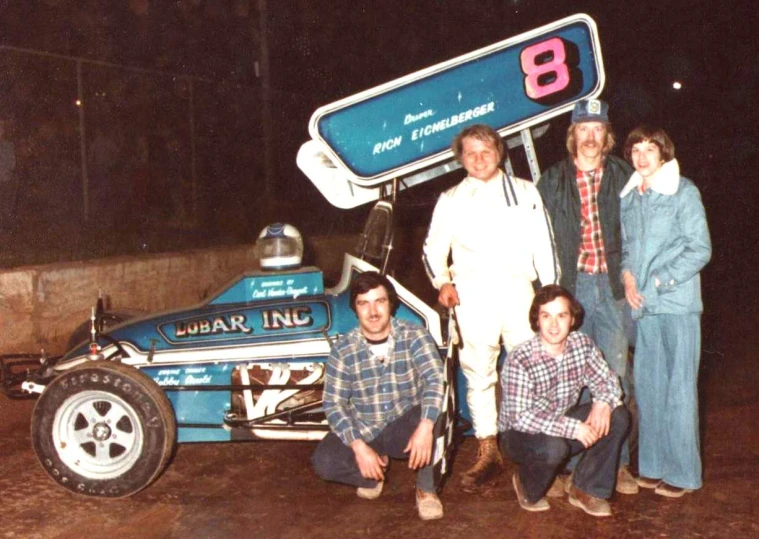 a man standing next to a race car holding the number 8