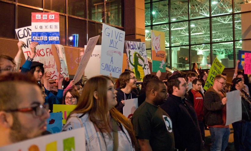 many people protesting against gender in front of an office building