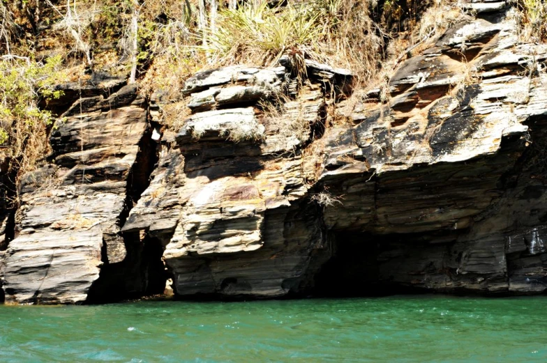 two people paddle a boat near a large rock outcrop
