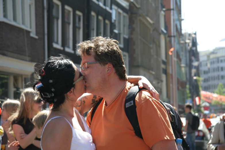 a man and a woman sharing a kiss in the middle of a crowd of people