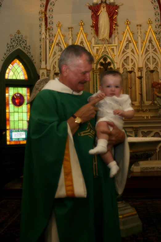 a priest holds his little baby next to his face