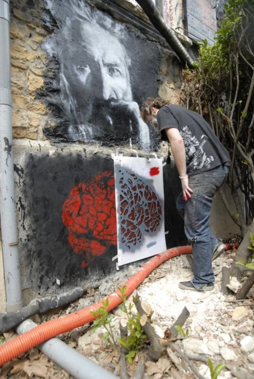 the man works on graffiti on the outside of the house