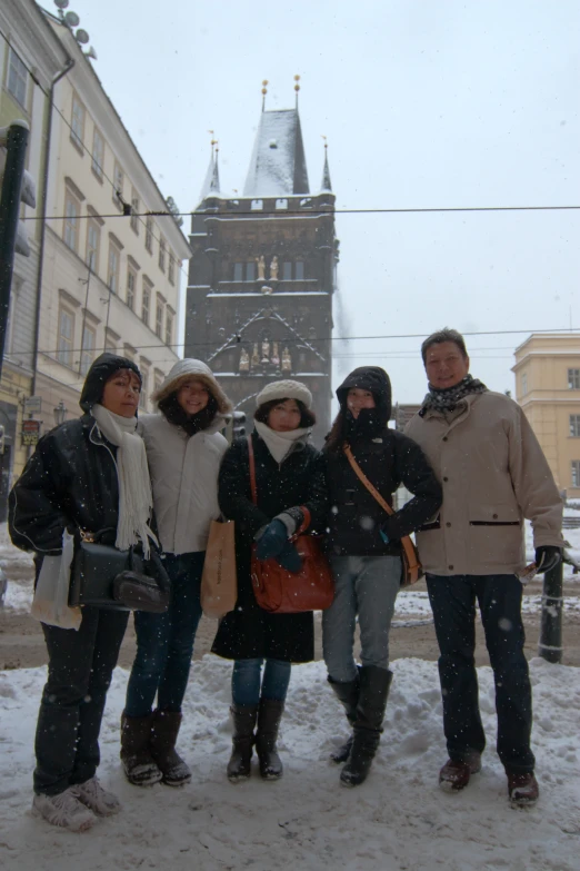 a group of people standing in the snow on a city street