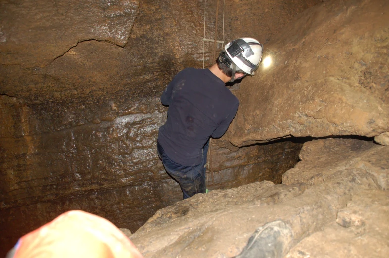 a person wearing a helmet walking in a cave