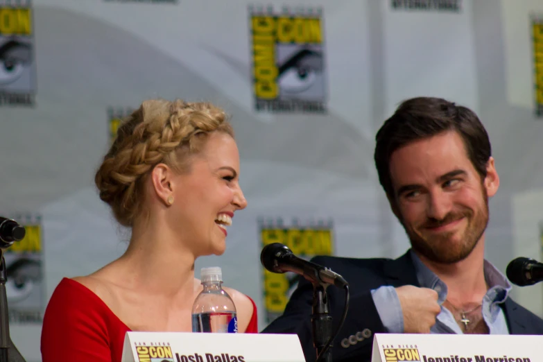 a woman is sitting at a microphone while two men are behind her