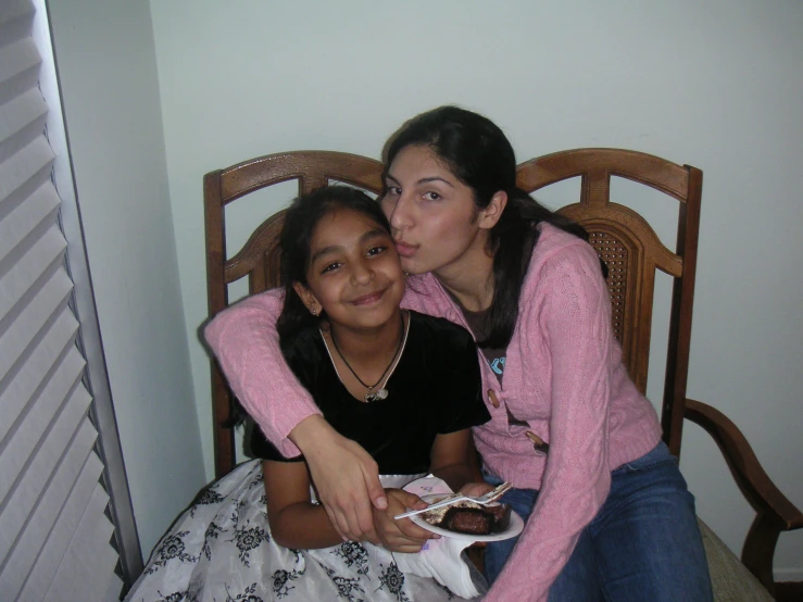 a woman and a girl sitting on a chair with plates of food