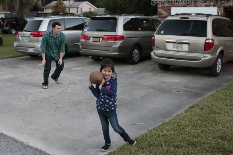 a girl holding a basketball in her hands while standing next to two other people