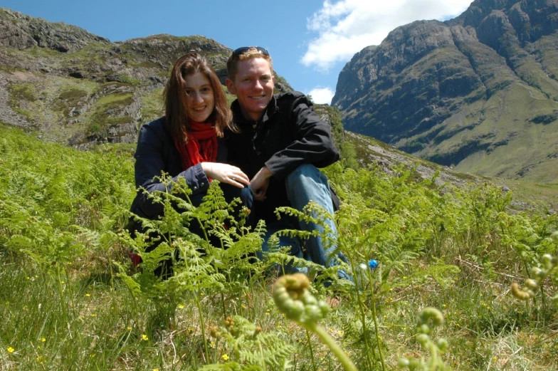 two people kneeling on a grass covered hillside