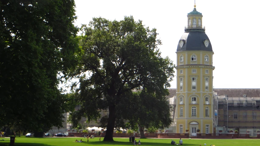 a large yellow clock tower towering over a lush green park