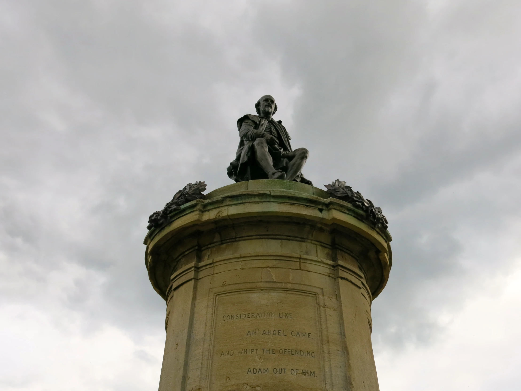 statue of a man sitting on top of a pillar