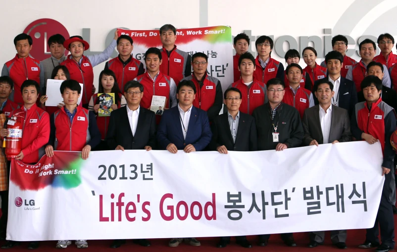 a bunch of people standing together behind a banner