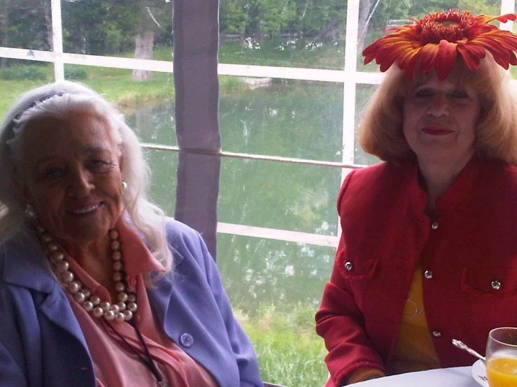 two women sitting by a window with fruit on their heads