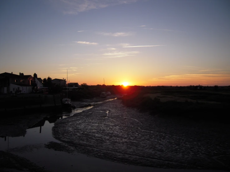 a river with sunset over houses and water