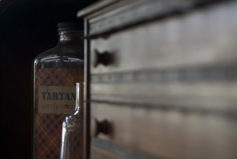 the bottle is full of tatto vodka next to a drawer