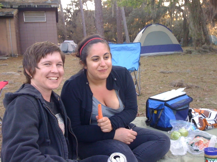 a woman and man sit on a blanket in a field